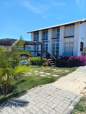 A building with a tiled roof, a staircase, and a paved pathway. - Cozy house surrounded by nature, close to the beach and lagoon in Arraial do Cabo. (Arraial do Cabo)