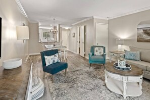 A spacious living room with a blue armchair, a teal armchair, a white coffee table, and a grey rug. -  2BR Villa w/ Pool • Walk to Coligny Beach, Dining, Shops & Park! (Hilton Head Island)