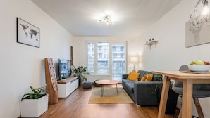 Una sala de estar moderna con un sofá, una mesa de centro, un televisor y un comedor con una mesa y sillas.