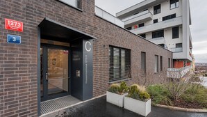 Un edificio moderno con fachada de ladrillo, puerta de cristal y un letrero que indica la dirección.