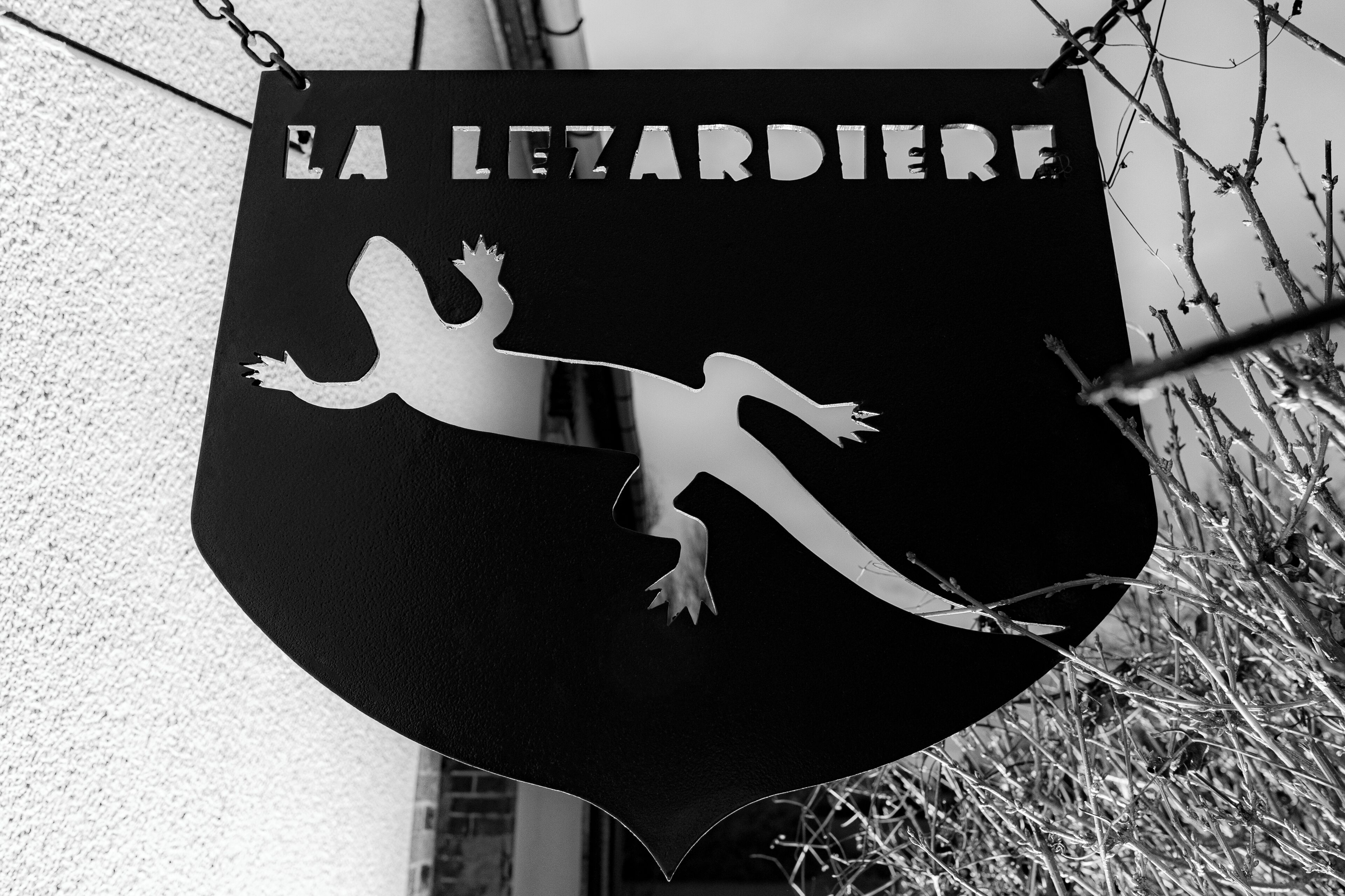 Een zwart-wit bord met de tekst 'EA LEZARDIERE' en een silhouet van een hagedis.