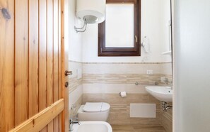 A small bathroom with a toilet, sink, and window. - Apartment With sea View and Great Roof Terrace (Santa Teresa di Gallura)