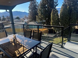 A balcony with a glass railing, outdoor furniture, and a view of a mountainous landscape. - Close to Wineries, The Beach, trails, and Downtown (Penticton)