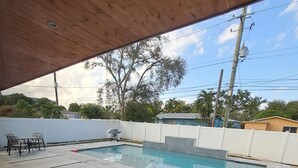 Un jardin avec une piscine, des meubles de patio et une clôture blanche.