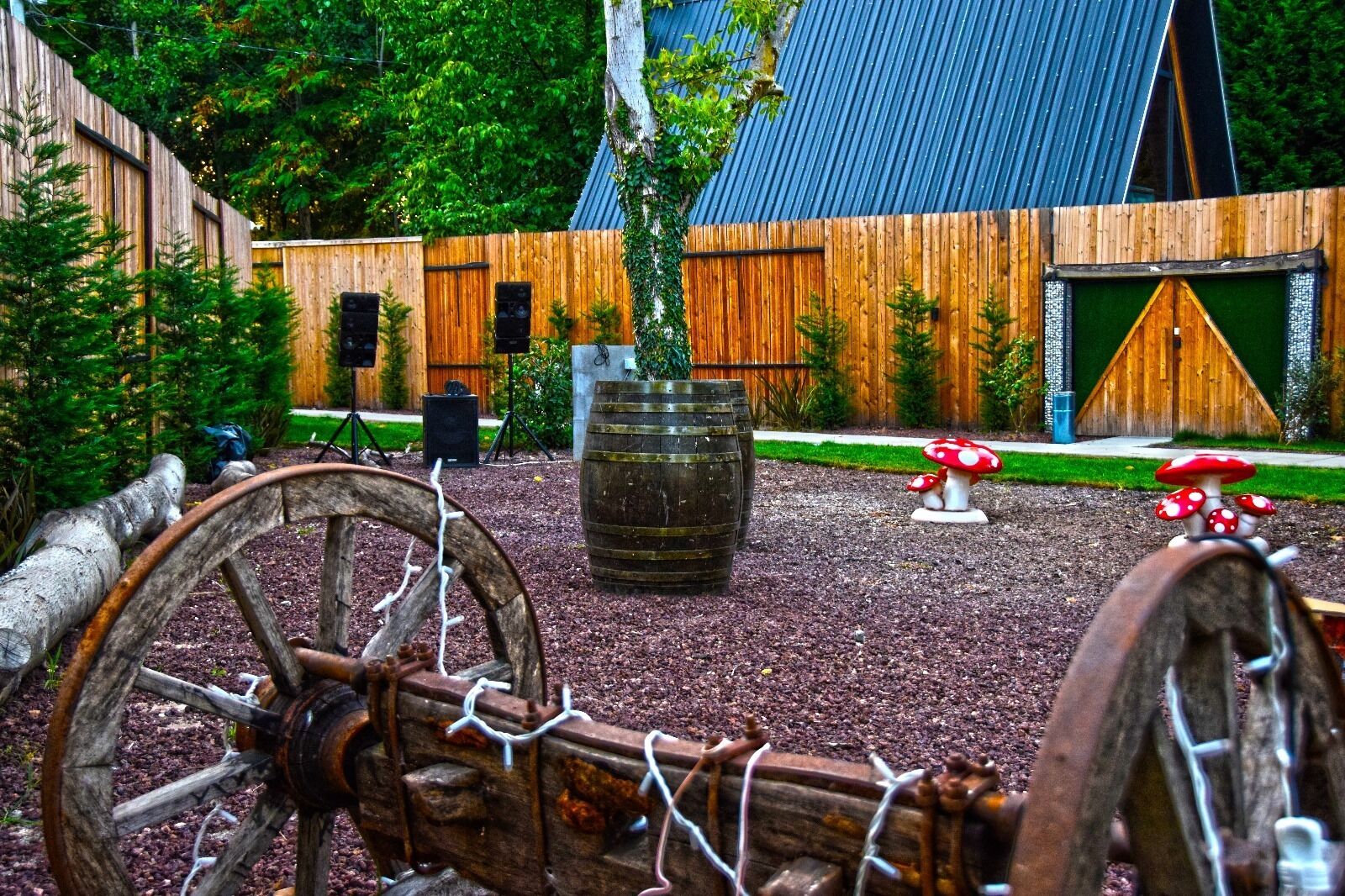 A rustic outdoor area with wooden fences, a large barrel, and mushroom sculptures.
