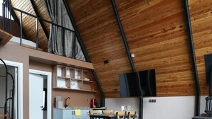 A spacious loft with a high ceiling, a kitchen area, a dining table, and a cozy seating area. - Big garden sapanca (Sapanca)
