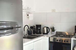 A modern kitchen with a stainless steel refrigerator, a gas stove, a coffee maker, and a sink.