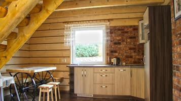 Una cocina rústica con armarios de madera, un ventanal con vistas y un comedor con mesa y sillas.