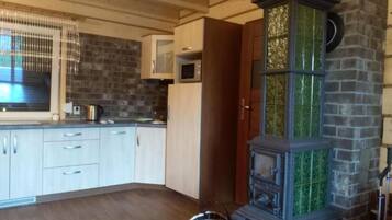 A kitchen with wooden cabinets, a microwave, and a green-tiled stove.