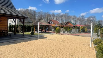 Una cancha de voleibol de arena con red, rodeada de edificios y árboles.