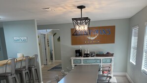 Una cocina moderna con una mesa de comedor grande, taburetes de bar y una lámpara colgante.