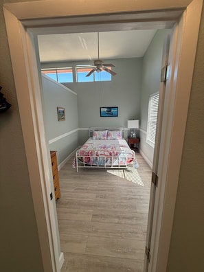 A bedroom with a bed, a ceiling fan, a window, and a nightstand.