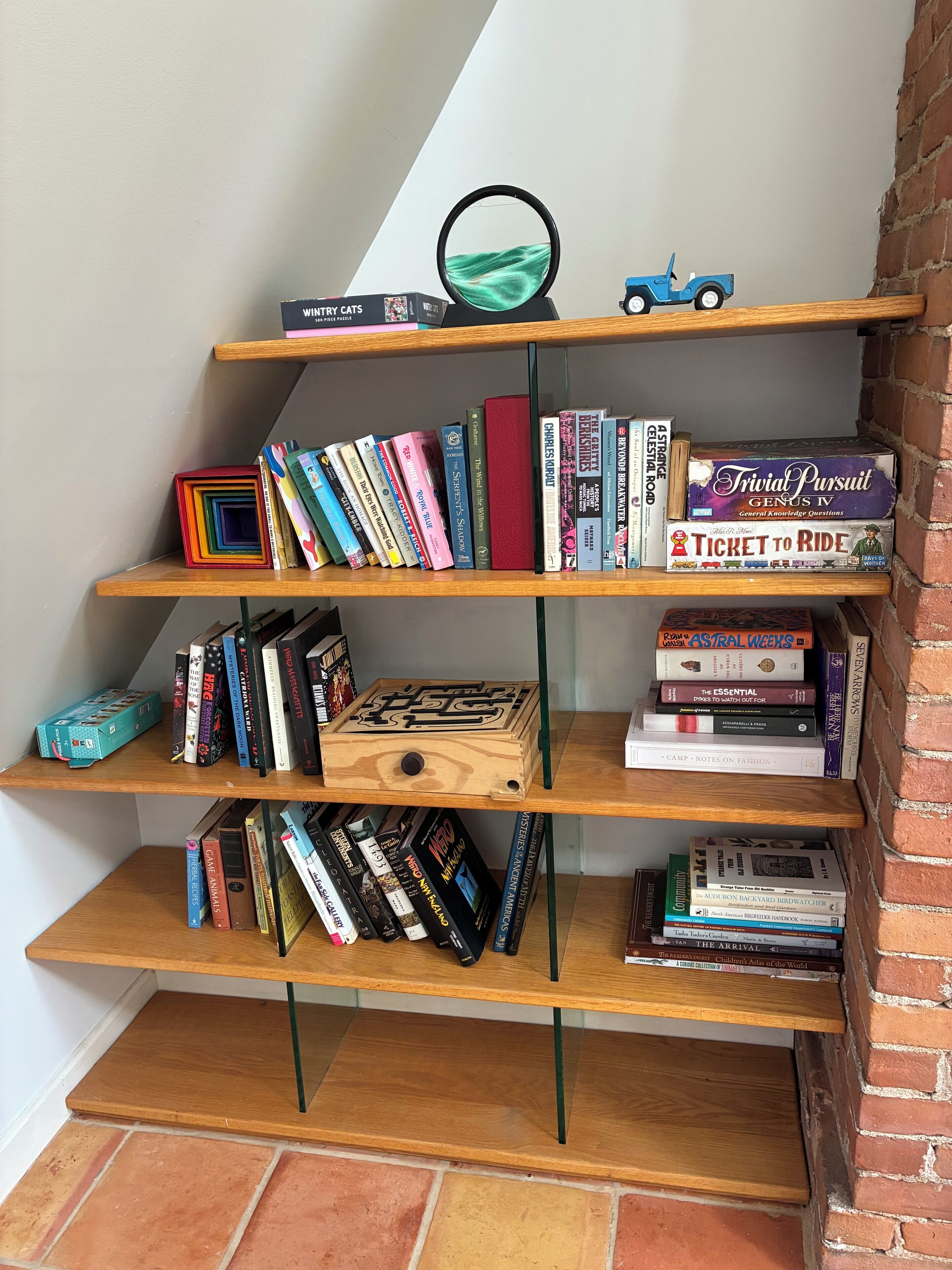 A wooden bookshelf with multiple shelves filled with books and a small toy car.