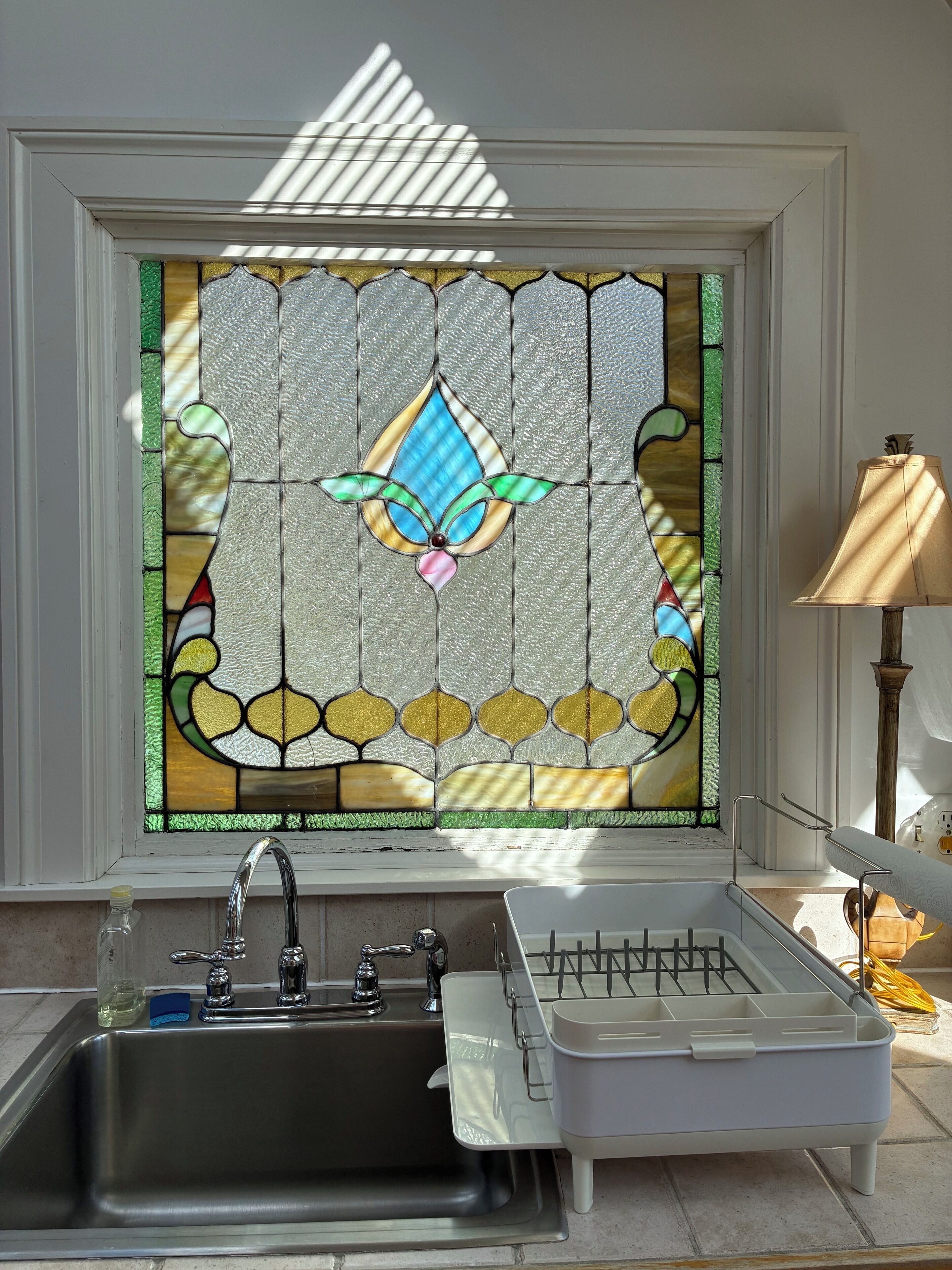 Un baño con un lavabo de acero inoxidable, una pileta blanca y una bandeja de vidrio.