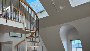 Un loft espacioso con escalera de caracol, un rincón de descanso acogedor y grandes ventanales con vistas al exterior.