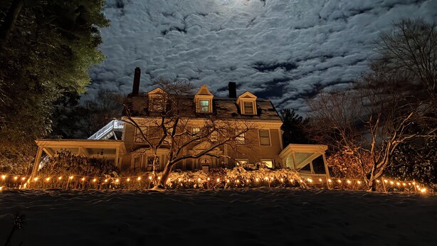 Una casa con una escalera que lleva a un porche, rodeada de nieve y luces decorativas.