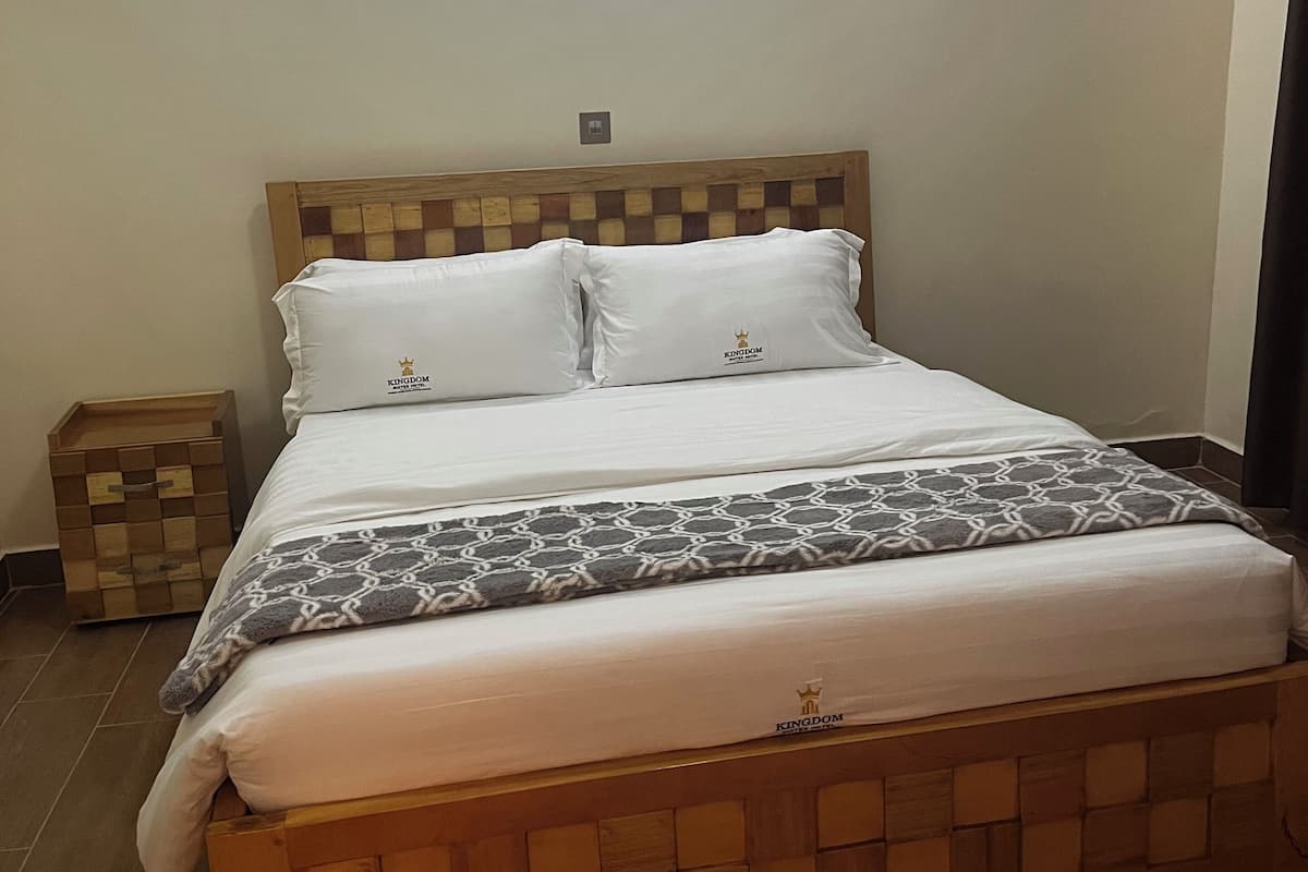 A bed with a wooden headboard, white bedding, and a patterned blanket.