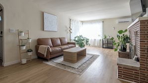 A living room with a brown leather sofa, a wooden coffee table, and a brick fireplace. - Spacious 7BR 4BA Home - Game Room - AC/Heat - 20 min to Airport (Kent)