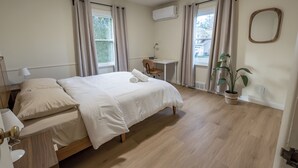 A bedroom with a bed, bedside table, lamp, desk, chair, potted plant, and an air conditioning unit. - Spacious 7BR 4BA Home - Game Room - AC/Heat - 20 min to Airport (Kent)