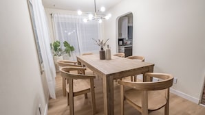A dining area with a wooden table and chairs, a vase with flowers, and a kitchen visible through an archway. - Spacious 7BR 4BA Home - Game Room - AC/Heat - 20 min to Airport (Kent)