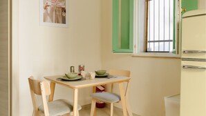 A small dining area with a table, two chairs, a window with green shutters, and a white refrigerator. - Cozy 1-bedroom house in the charming historic center of Noto (Noto)
