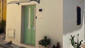 A building with a green door, a sign reading "Chez Louise," and potted plants. - Cozy 1-bedroom house in the charming historic center of Noto (Noto)
