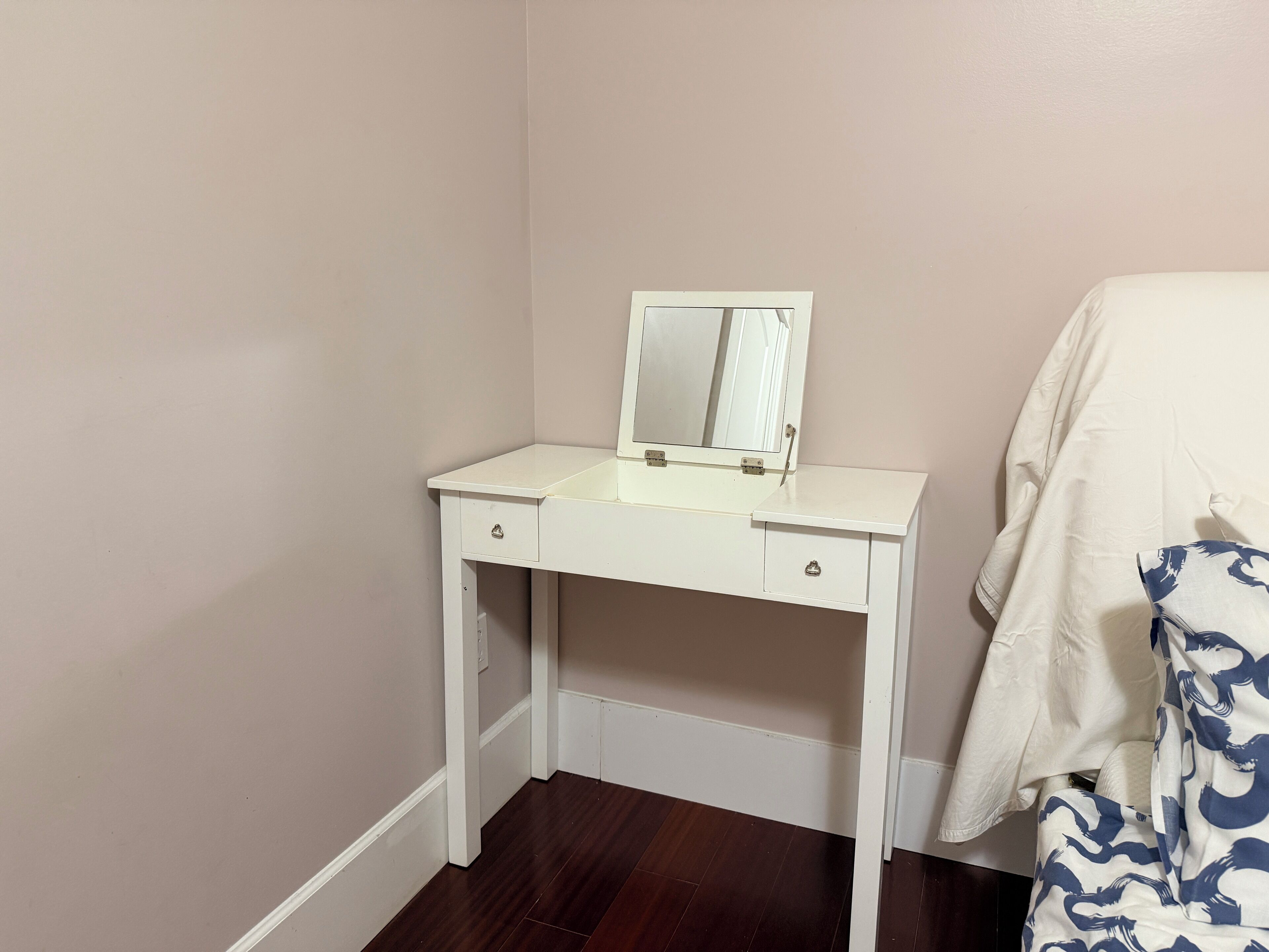 Une commode blanche avec un miroir, deux tiroirs et un petit placard.