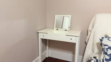 Une commode blanche avec un miroir, deux tiroirs et un petit placard.