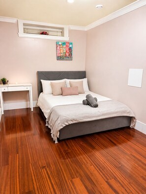 A bedroom with a bed, bedside table, and a painting on the wall.