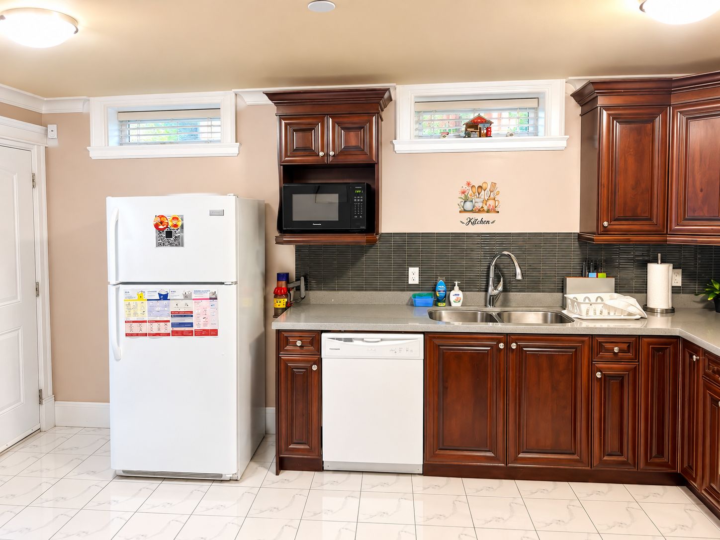 Una cocina equipada con refrigerador, microondas, lavamanos y armarios de madera.