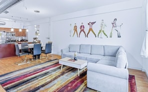 A modern living room with a grey sofa, a coffee table, and a colorful striped rug. - `Celebrating Elvis` Loft - Steps from Main St (Memphis)
