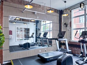A gym with treadmills, a mirrored wall, and a large window. - `Celebrating Elvis` Loft - Steps from Main St (Memphis)