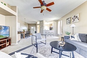 A spacious living room with a ceiling fan, a television, a dining area, and a kitchen in the background. - 3BR | Screened Pool | 5-Game Room | Lake 9-Min Walk | 10 Min Disney | Sleeps 9 (Davenport)