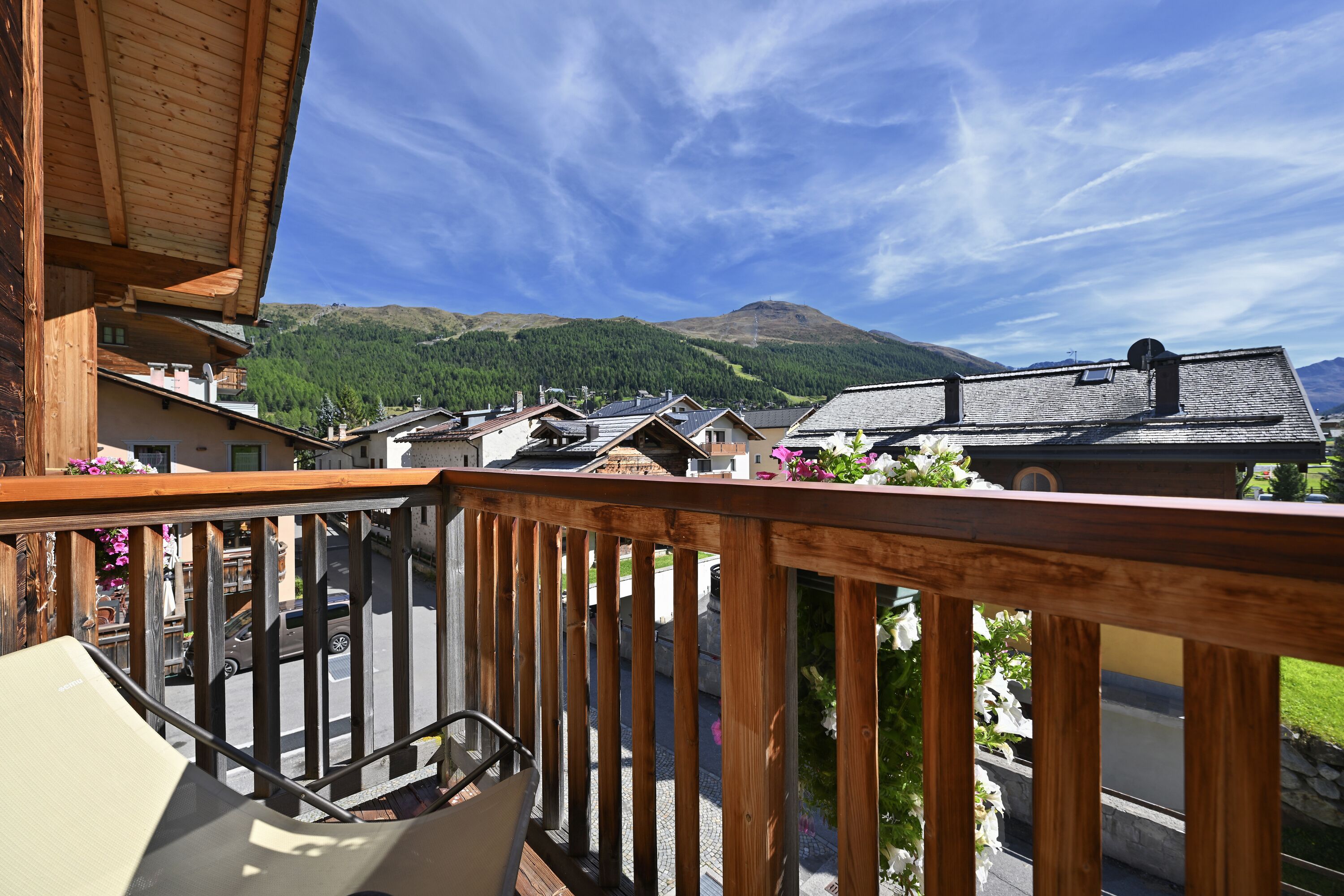 A wooden balcony with a view of a mountain and a village.
