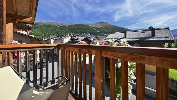A wooden balcony with a view of a mountain and a village. - Bio Hotel Villa Cecilia (Livigno)