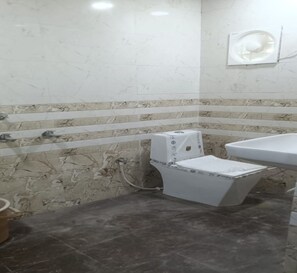A bathroom with a toilet, a sink, and a wall-mounted mirror. - Hotel AramNest (Raebareli)