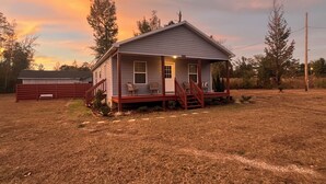 A single-story house with a porch, a small deck, and a front yard.