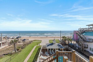 A beachfront property with a pool, lounge chairs, and a view of the ocean.