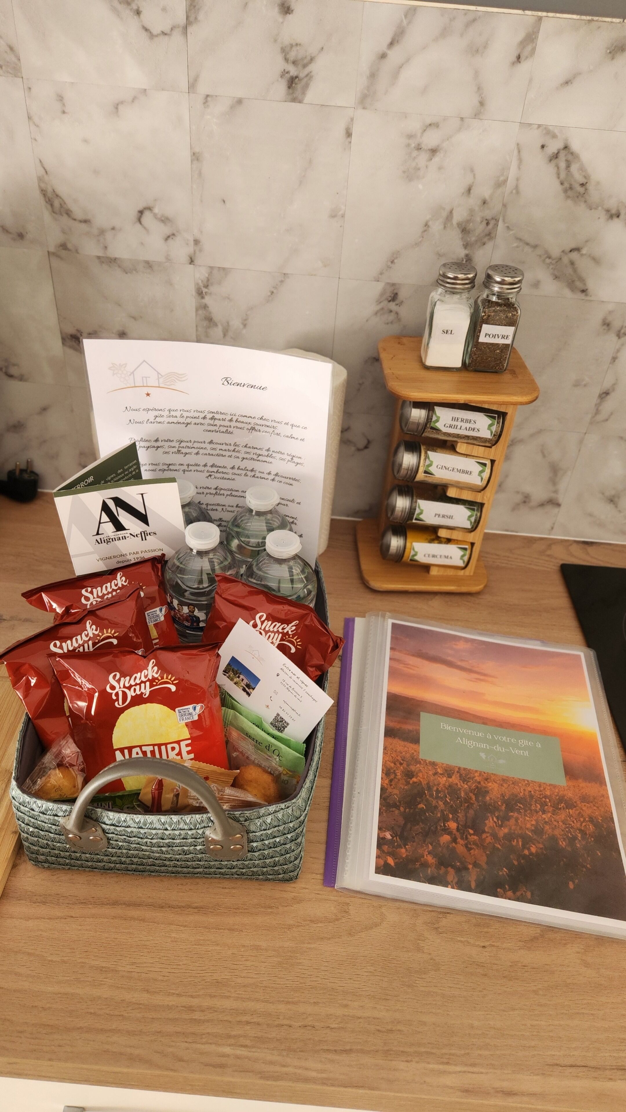 A welcome package with a booklet, snacks, and a bottle of water on a wooden table.