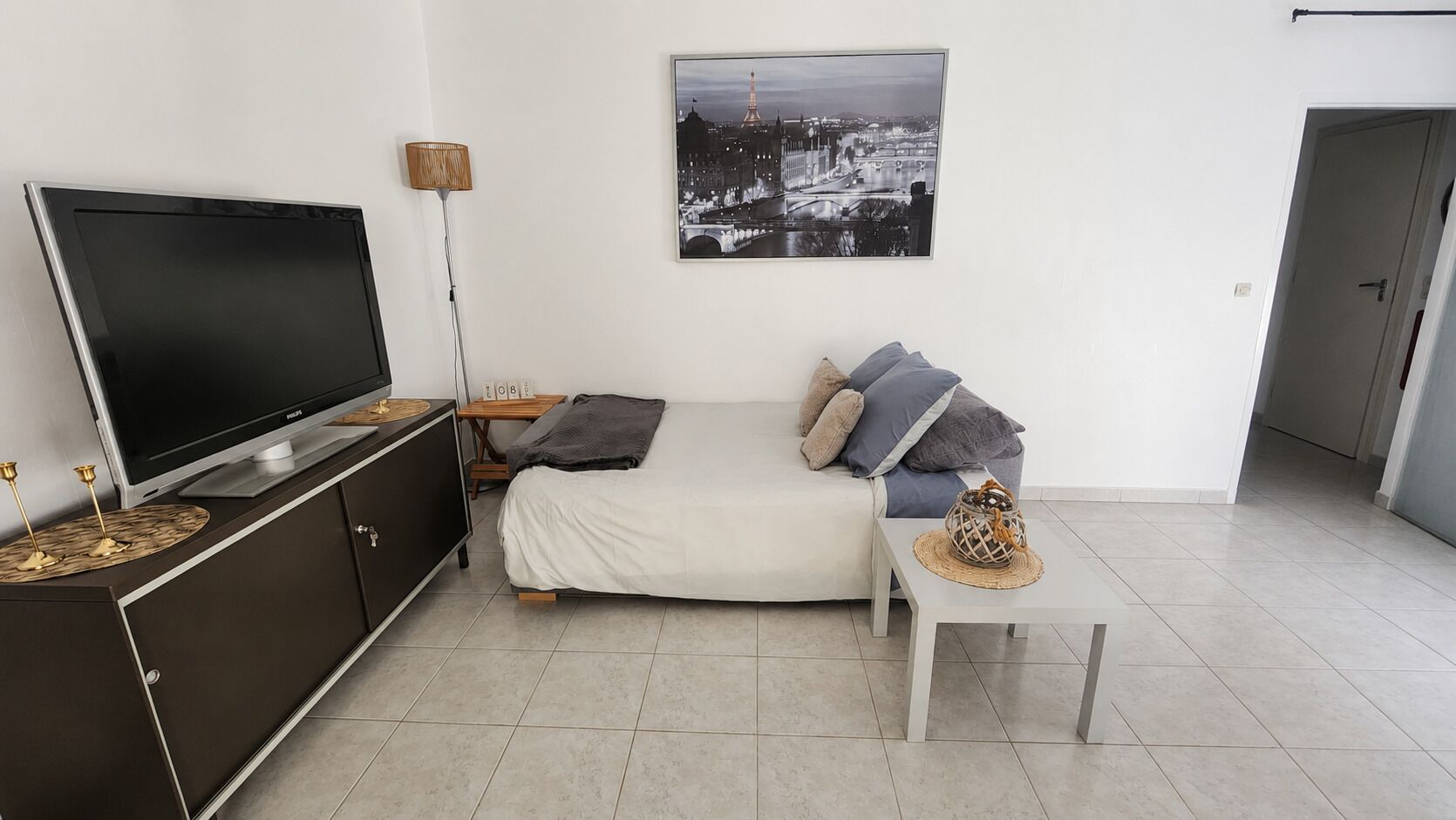 Een moderne woonkamer met een flatscreen televisie, een bank, een salontafel en een lijst met een stadsgezicht aan de muur.