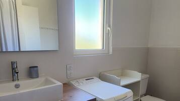 Une salle de bain avec un lavabo, un miroir, des toilettes et une fenêtre.