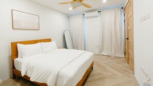 Une chambre à coucher avec un lit, un ventilateur de plafond, un appareil de climatisation et une porte.