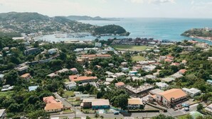 Une ville côtière dotée d’un port de plaisance, de bâtiments résidentiels et d’un paysage vallonné en arrière-plan.