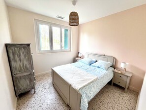 Une chambre à coucher comprenant un lit, des tables de chevet, une armoire et une fenêtre avec des rideaux.