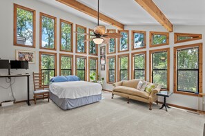 A spacious bedroom with a large bed, a sofa, a desk, and multiple windows offering a view of the outdoors. - Cozy modern style home 4.4 miles from Augusta National (Augusta)