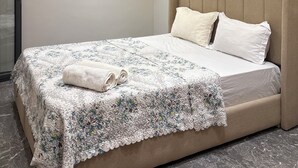 Une chambre à coucher moderne avec un grand lit, une tête de lit et des spots encastrés au plafond.