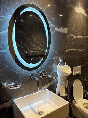 Ein Badezimmer mit Marmorwaschtisch, modernem Wasserhahn, Handtuchhalter mit Handtuch und Toilette.