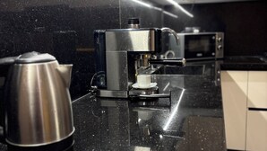 Une cuisine équipée d’une machine à café, d’une bouilloire et d’un four à micro-ondes.