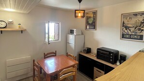 Una cocina compacta con una mesa y sillas de madera, un microondas, un tostador y un refrigerador.