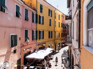 A narrow street with colorful buildings, outdoor seating, and a pedestrian walkway. - Apartment Milena by Interhome (Imperia)